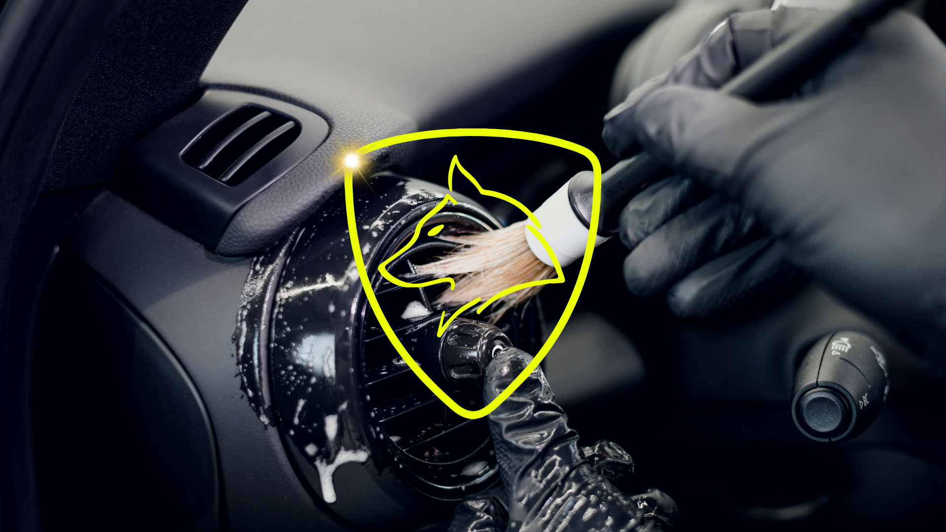 Nettoyage de précision des grilles d'aération d'une voiture avec pinceau et mousse nettoyante.