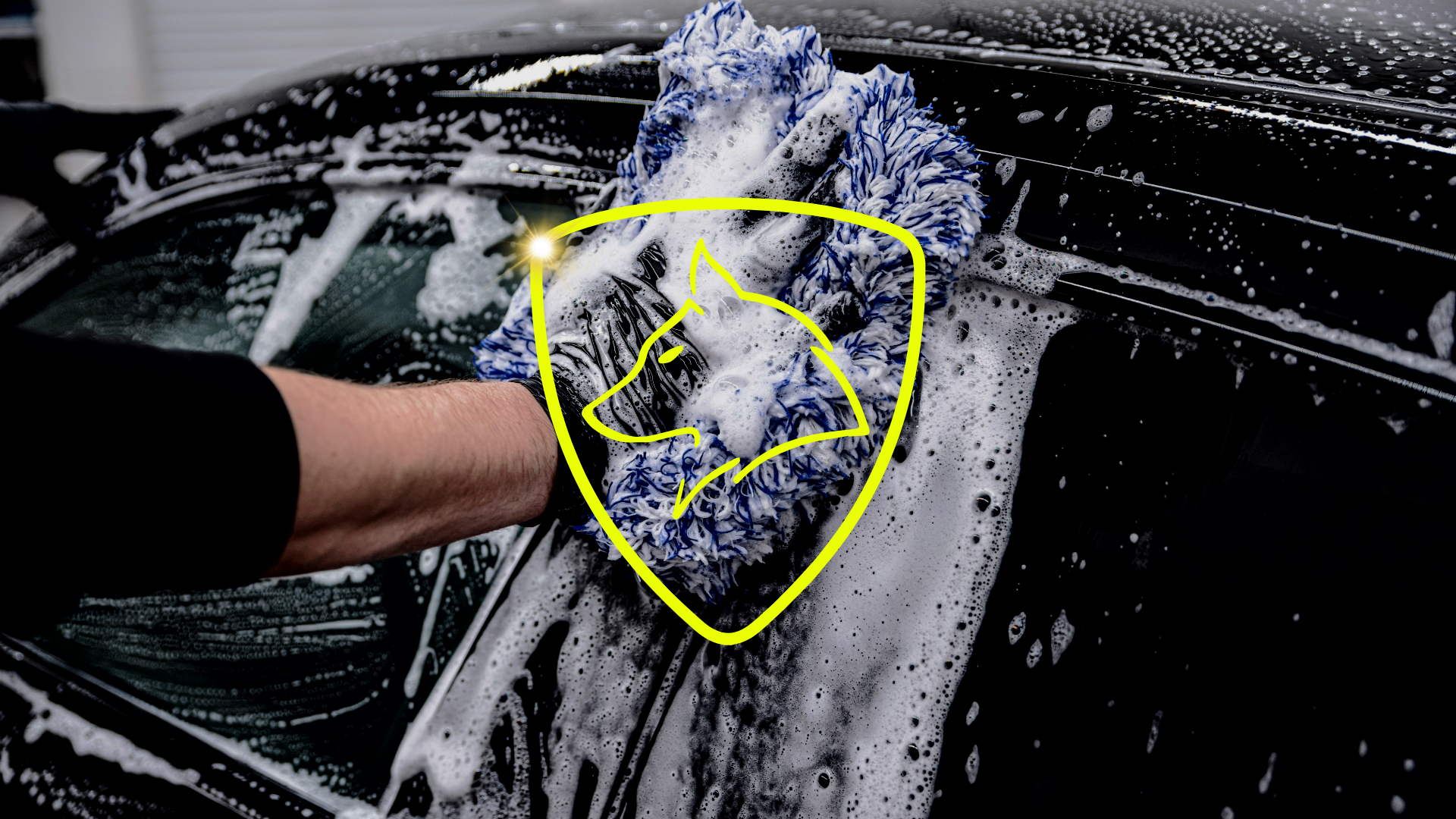 Lavage manuel de carrosserie à l'aide d'un gant microfibre et mousse active pour éviter les micro-rayures.